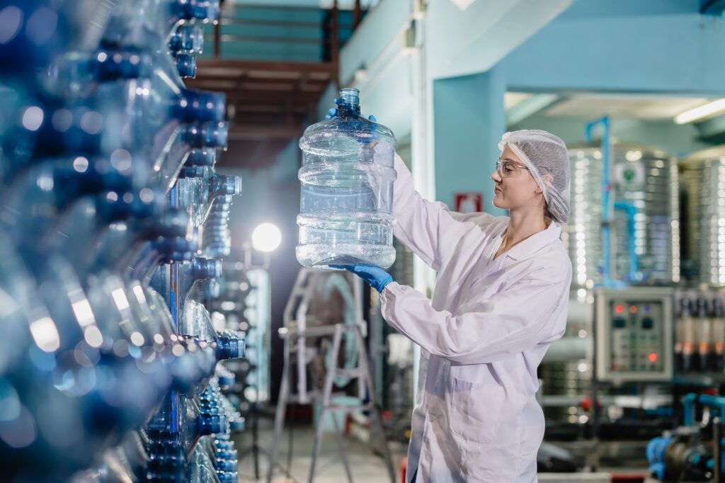 Women worker in drinking water factory work checking water bottle gallon storage warehouse.